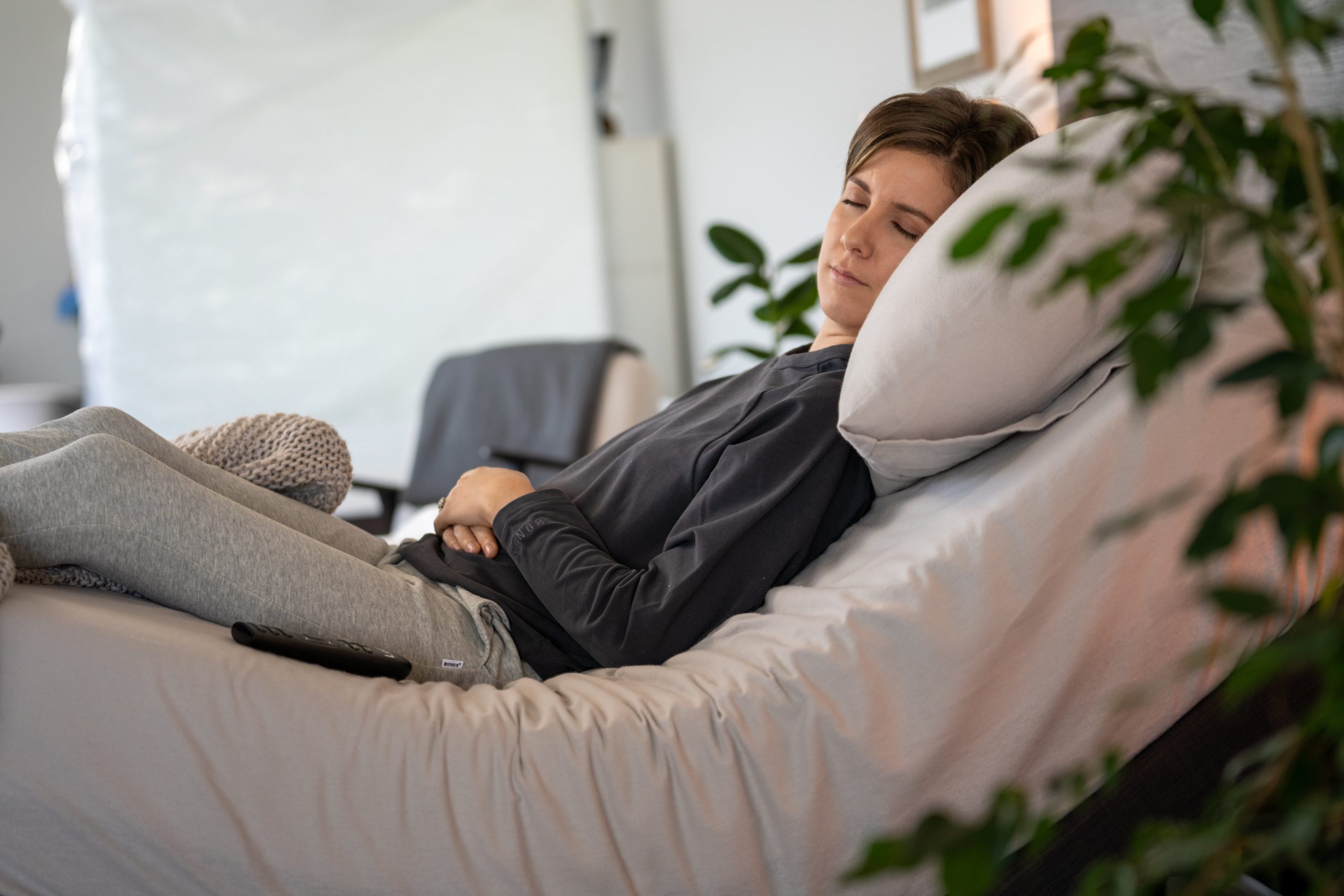 Person resting comfortably on an adjustable bed with the head and knees slightly elevated, showing how an adjustable mattress base can support spinal alignment and relieve lower back pressure.